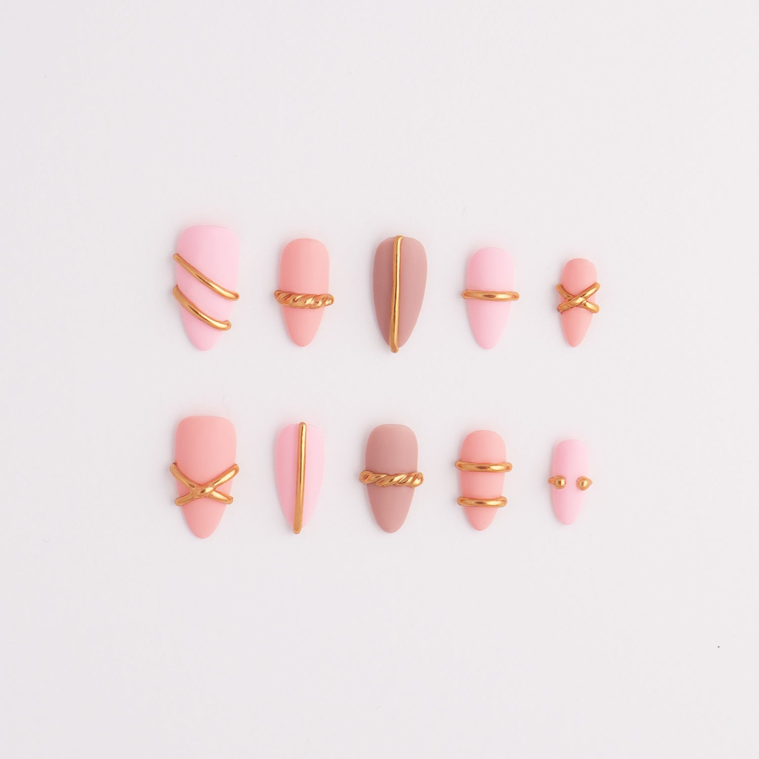 Pink press-on nail art designs with gold accents on a light gray background